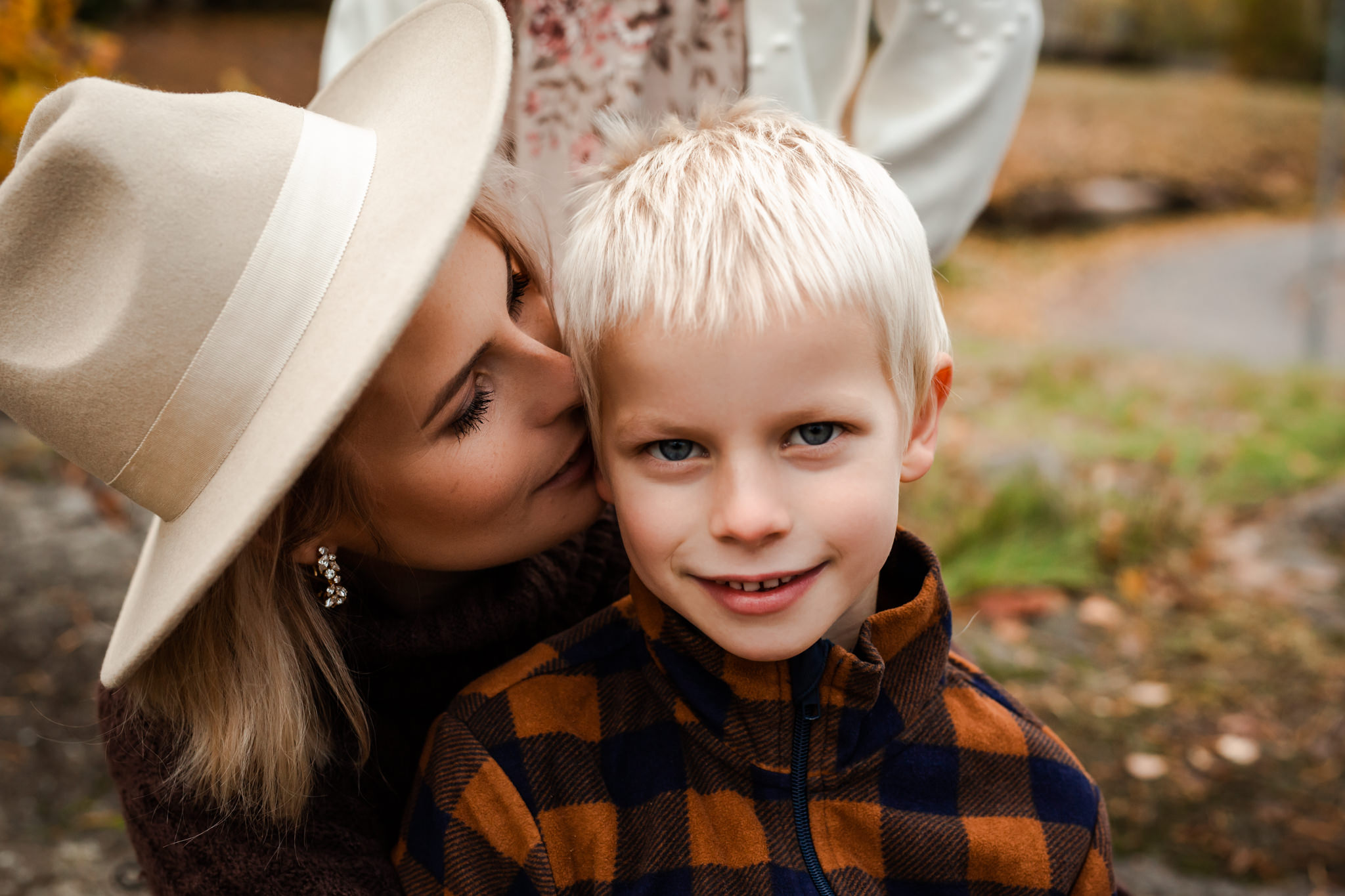 Familjefotografering utomhus i Eksjö där en mor pussar sin son på kinden.