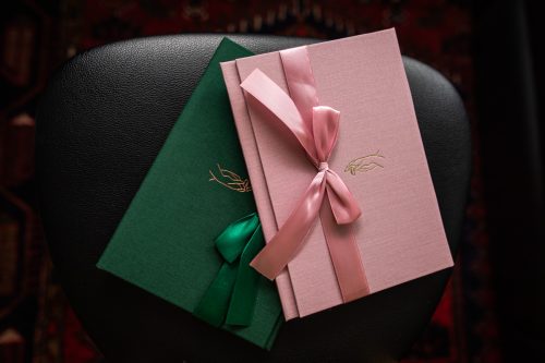 Inslagna album i rosa och grönt med sidenband och präglat motiv på