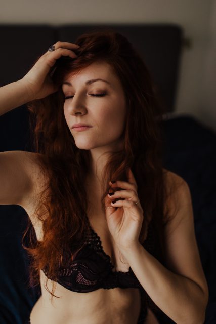 Kvinna i underkläder leker med sitt hår under en boudoirfotografering i Stockholm