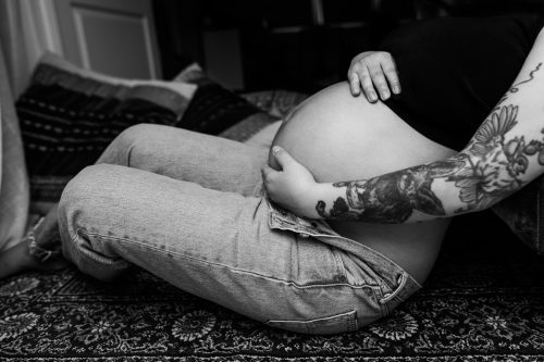 En gravid kvinna sitter på golvet och håller om sin gravidmage