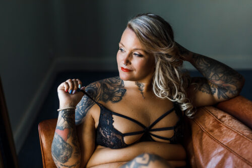 Plus size kvinna sitter i en fåtölj i svarta underkläder på en boudoirfotografering i Småland
