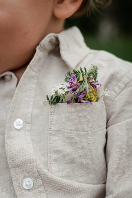 Närbild på ett barns skjorta med en bröstficka full med ängsblommor