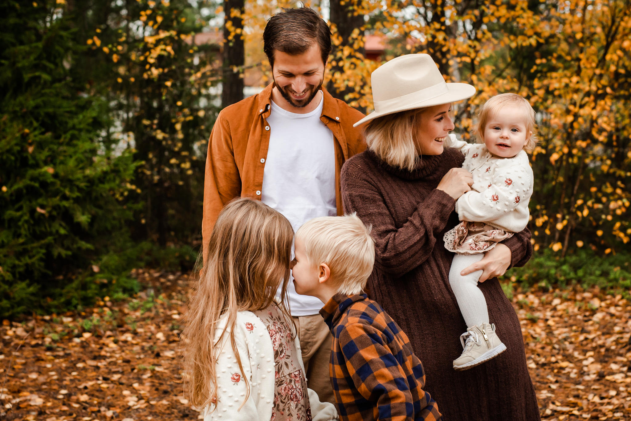 En familj som busar i höstfärgerna på sin familjefotografering i Småland