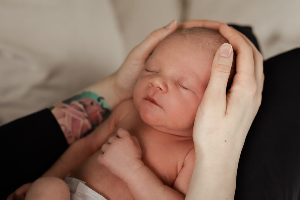 Nyfödd bebis sover i sin mammas famn under en nyföddfotografering i Småland.