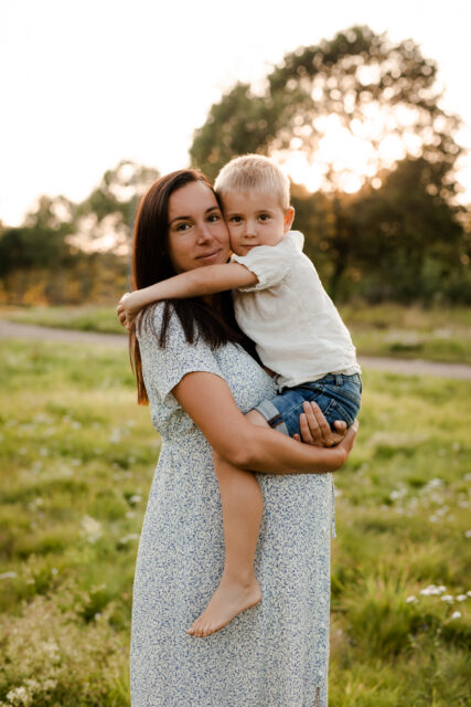 En gravid kvinna bär sin son i solnedgången på en gravidfotografering i Eksjö