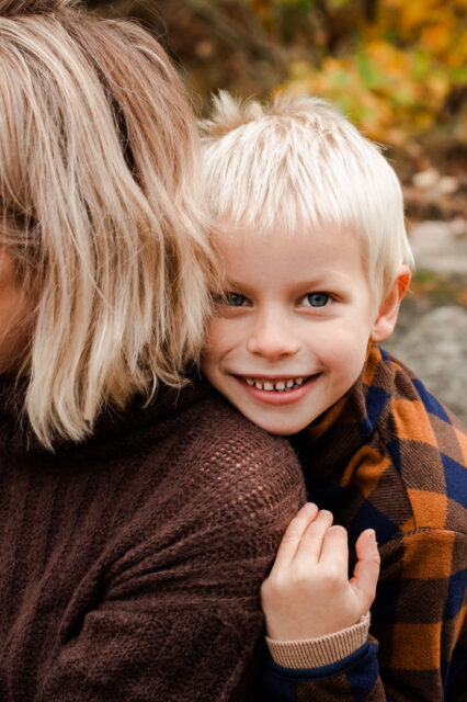 Blond pojke håller om sin mammas axel.