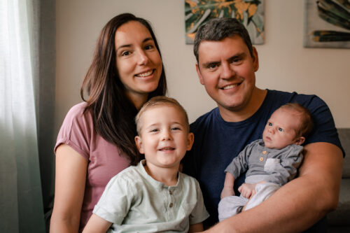 En familj sitter tillsammans med sin nyfödda bebis och sin 4-åriga son.