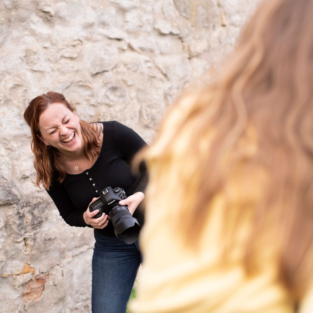 Fotograf Mia Modigh Westlund skrattar med en kamera i handen